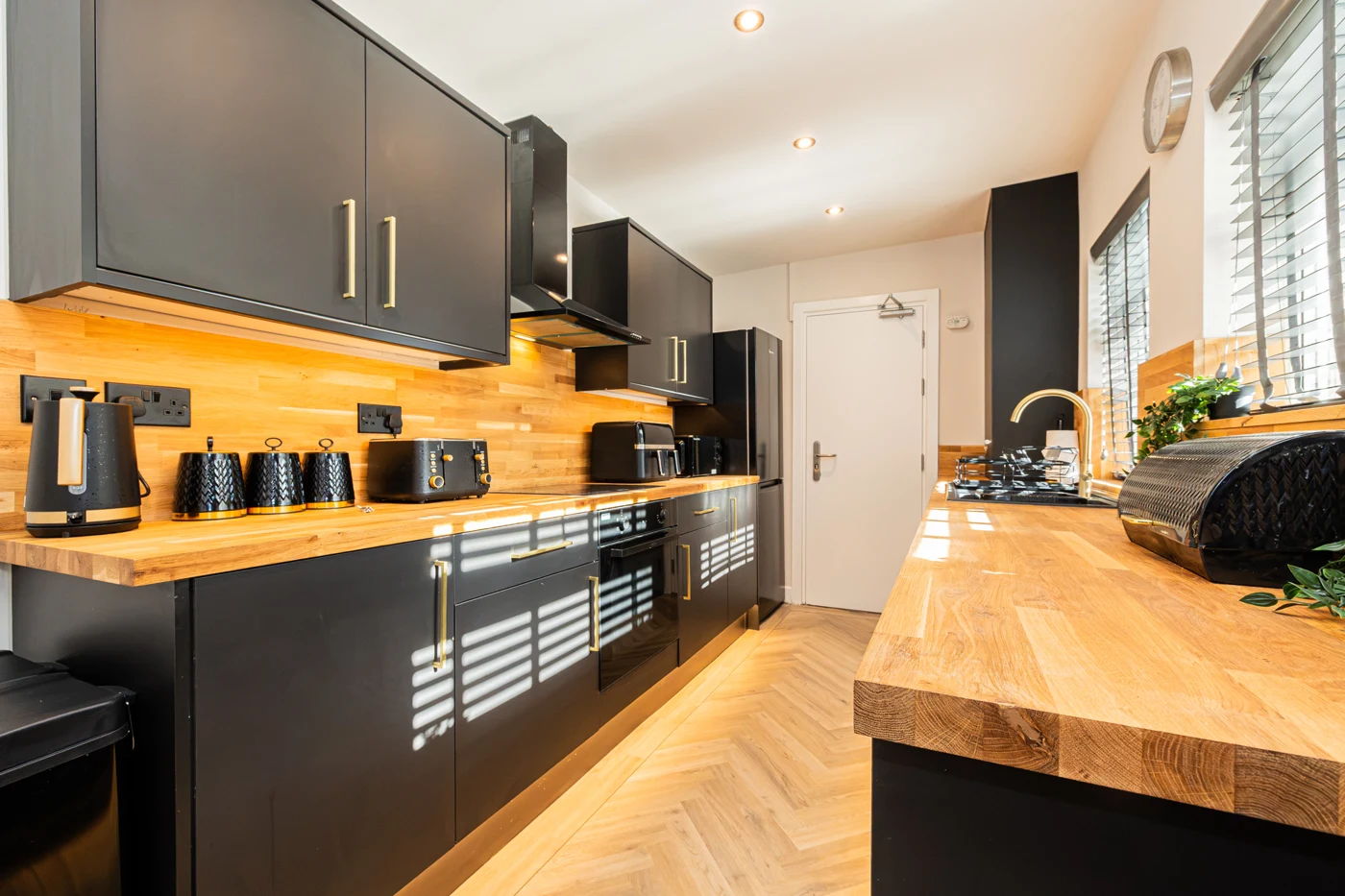 Modern fitted kitchen with charcoal cupboards and timber worktops